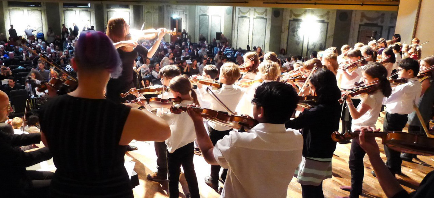 Young people playing the violin to an audience