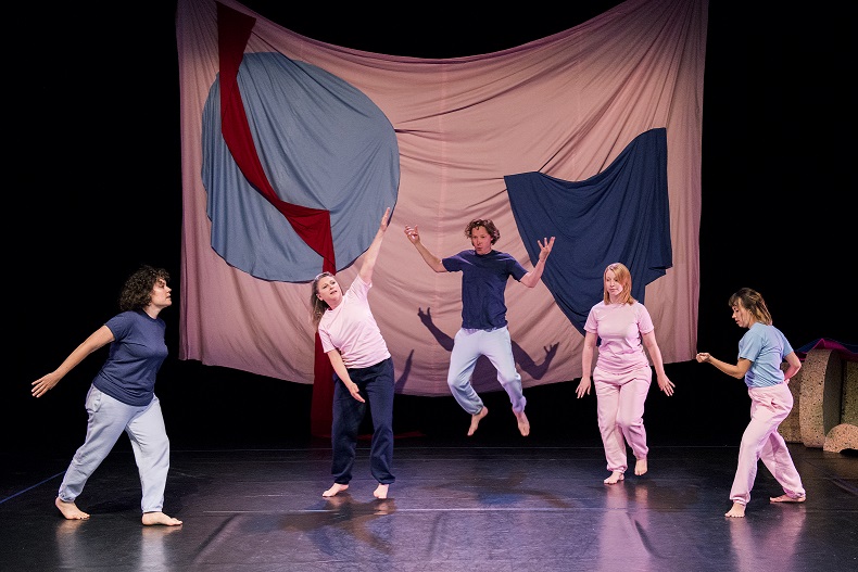 Performers jumping in front of a curtain